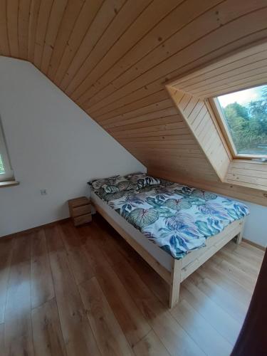 a bed in a room with a wooden ceiling at Domek letniskowy Klimkówka 182 in Ropa