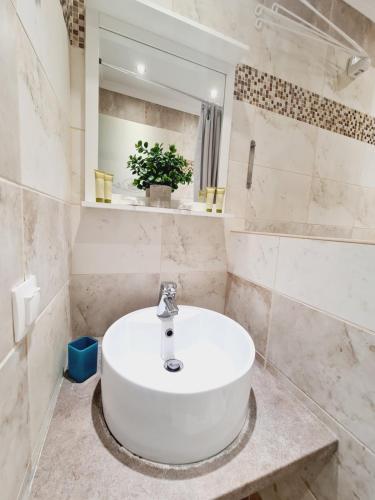 La salle de bains blanche est pourvue d'un lavabo et d'un miroir. dans l'établissement Malibu Summer Studios, à Dassia