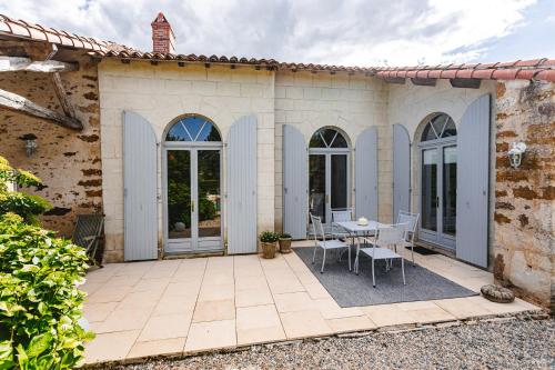 a patio of a house with a table and chairs at Logis La Tour - Gîte Orangerie in Saint-Laurent-de-la-Salle