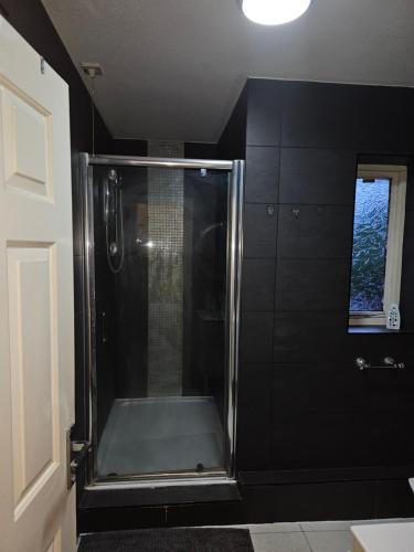 um chuveiro na casa de banho com paredes pretas e uma janela em Chi's Luxurious Home em Aveley