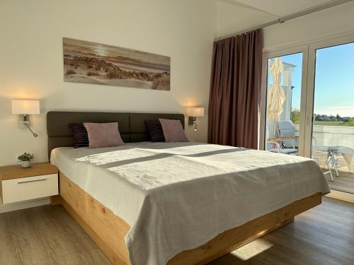 a bedroom with a large bed and a balcony at Haus Concordia 2 Lieblingsort in Thiessow