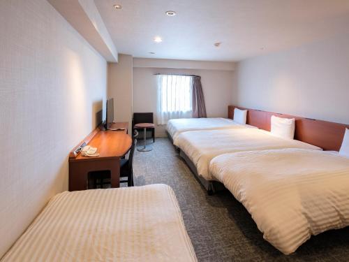 Vessel Hotel Miyakonojo في مياكونوجو: غرفه فندقيه ثلاث اسره ومكتب