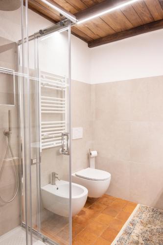 a bathroom with a toilet and a glass shower at LA TORRE DELLA RIPA in Tarquinia