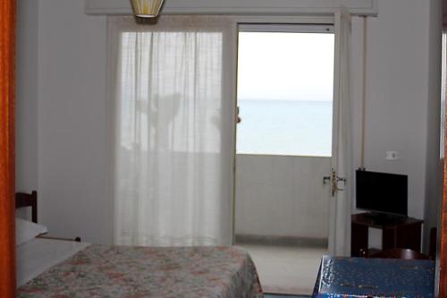 a bedroom with a bed and a sliding glass door at Hotel Piccolo Paradiso in Bordighera