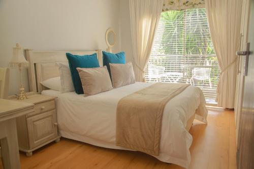 a bedroom with a bed with blue pillows and a window at InnJoy Boutique Hotel in Centurion
