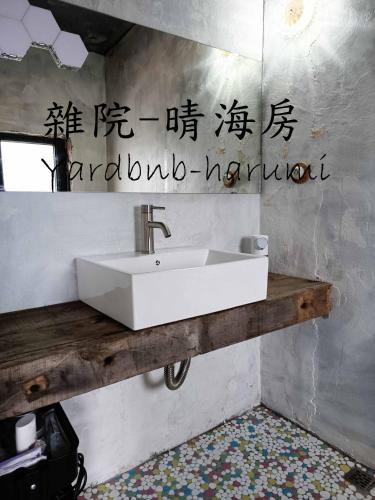 a white sink in a bathroom with writing on the wall at 雜院-晴海 新北市民宿證號333號 in Jiufen
