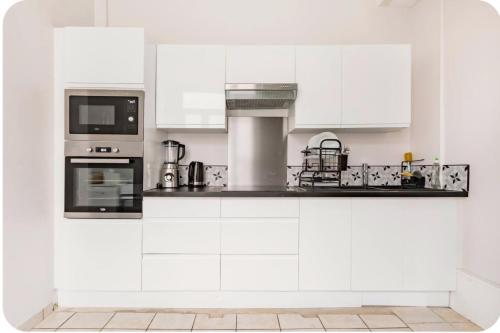 uma cozinha branca com armários e electrodomésticos brancos em Lille près du CHU Lille em Lille