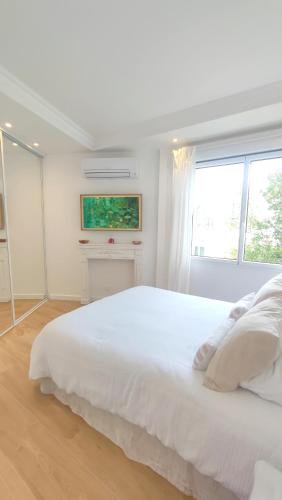 une chambre blanche avec un grand lit blanc et une fenêtre dans l'établissement La Dolce Vita de Cannes: Luxury city center apartement, beautiful View, à Cannes