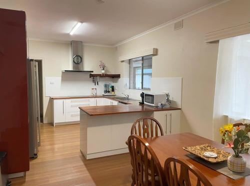 a kitchen with a dining table and a kitchen with white cabinets at The Hidden Gem Exquisite 3BR Retreat in Berri in Berri