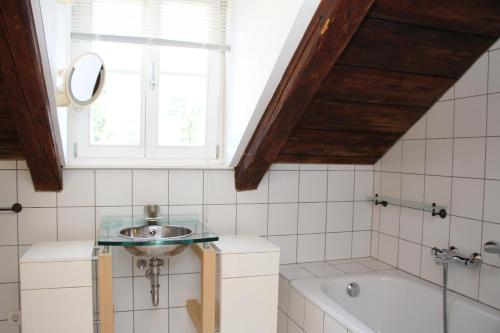 een badkamer met een wastafel, een bad en een raam bij Apartmenthaus Brunnenhof in Papstdorf