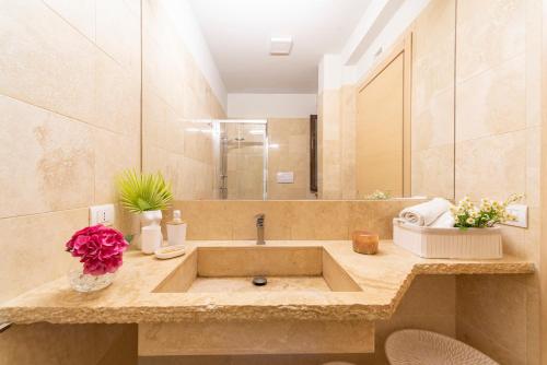 a bathroom with a sink with flowers on a counter at COCO SUNSHINE Apartment TAORMINA in Taormina