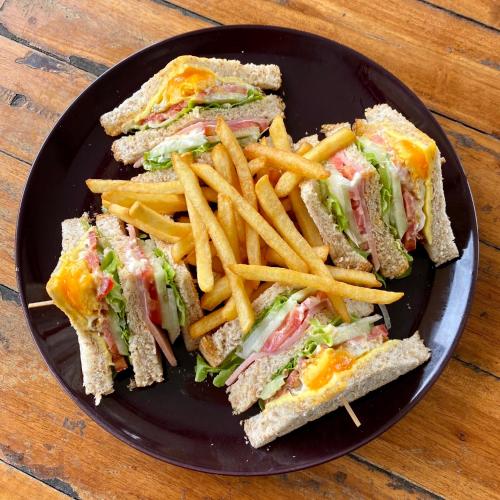 a black plate with a sandwich and french fries at Rainbow Bungalow Haadrin Koh Phangan in Haad Rin