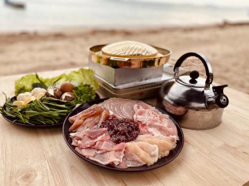 a table with a plate of meat and vegetables and a tea pot at Rainbow Bungalow Haadrin Koh Phangan in Haad Rin