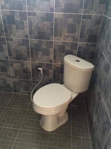 a bathroom with a white toilet in a tiled wall at Rainbow Bungalow Haadrin Koh Phangan in Haad Rin