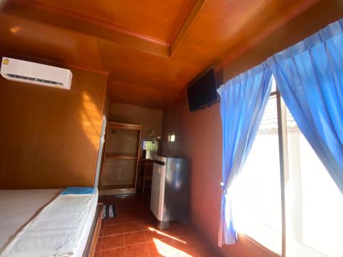 a bedroom with a bed and a window with blue curtains at Rainbow Bungalow Haadrin Koh Phangan in Haad Rin