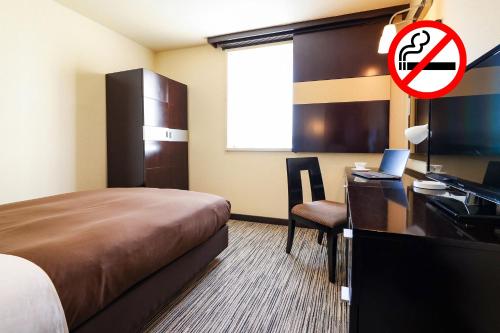 a hotel room with a bed and a desk with a computer at Fukui Hotel in Obihiro