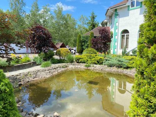 un jardín con un estanque frente a una casa en Hotel Zoloti Vorota en Lalovo