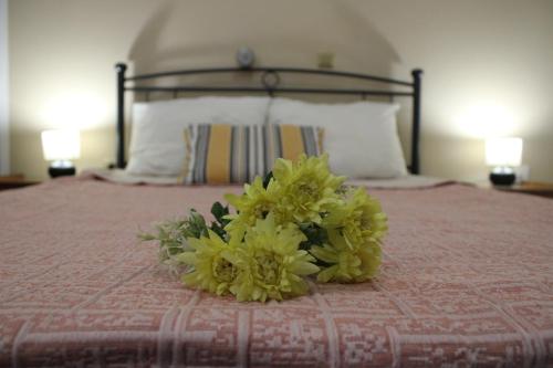 a bouquet of yellow flowers sitting on top of a bed at Rodi Apartment 2 in Kamari