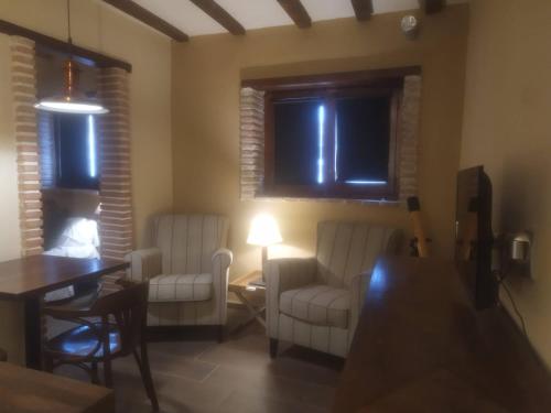 ein Wohnzimmer mit 2 weißen Stühlen und einem Tisch in der Unterkunft Alojamientos molino de revolcadores in Cañada de la Cruz