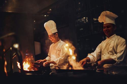 two chefs standing in a kitchen preparing food at Grand Hyatt Mumbai Hotel and Residences in Mumbai