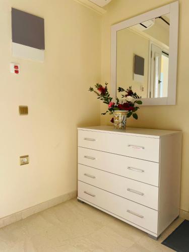 a dresser with a mirror and a vase with flowers on it at ELIA in Doukádes
