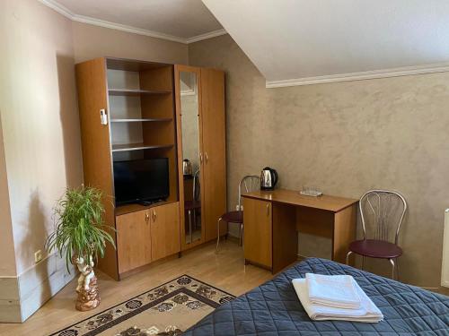 a bedroom with a bed and a desk and a television at Hotel Zoloti Vorota in Lalovo