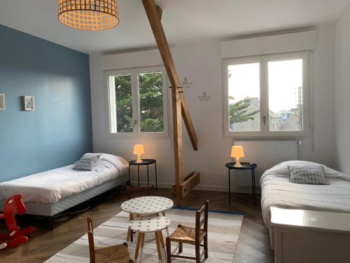une chambre avec deux lits et une table et des chaises dans l'établissement St Malo - Rothéneuf, proche Mont St Michel et Cancale, grande maison familiale, à Saint-Malo