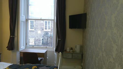 a bedroom with a window and a table and a desk at IVY- Braveheart Guest House in Edinburgh