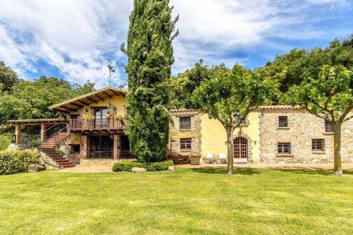an exterior view of a house with a large tree at Casa Rural Can Mananna Lloguer íntegre in Sant Feliu de Buixalleu
