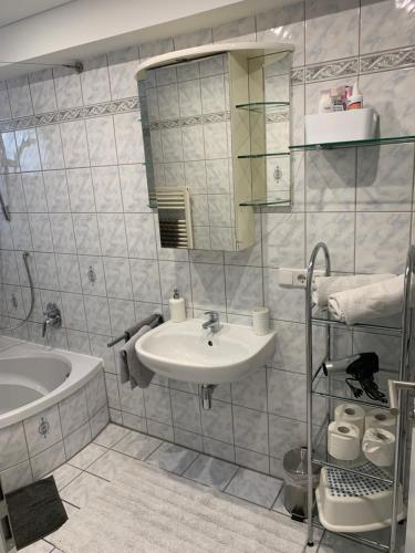 a bathroom with a sink and a mirror and a tub at Pension Ella in Kaltensondheim