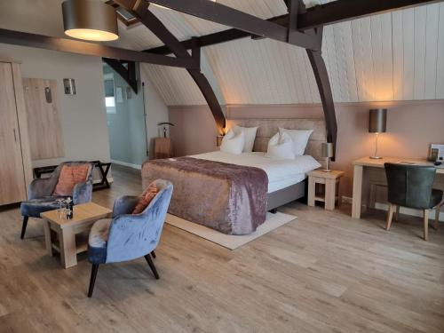 a bedroom with a bed and two chairs and a table at Herberg Welgelegen in Katwijk