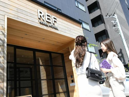 two women walking in front of a building at REF Kyoto Hachijoguchi by VESSEL HOTELS in Kyoto