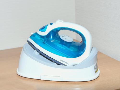 a white and blue iron sitting on a table at REF Kyoto Hachijoguchi by VESSEL HOTELS in Kyoto