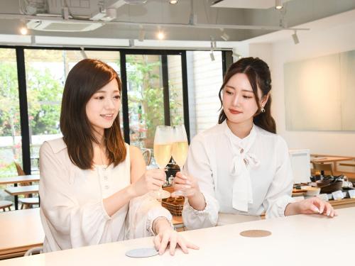 two women sitting at a table with a glass of wine at REF Kyoto Hachijoguchi by VESSEL HOTELS in Kyoto