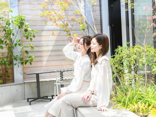 two women sitting on a bench looking at each other at REF Kyoto Hachijoguchi by VESSEL HOTELS in Kyoto