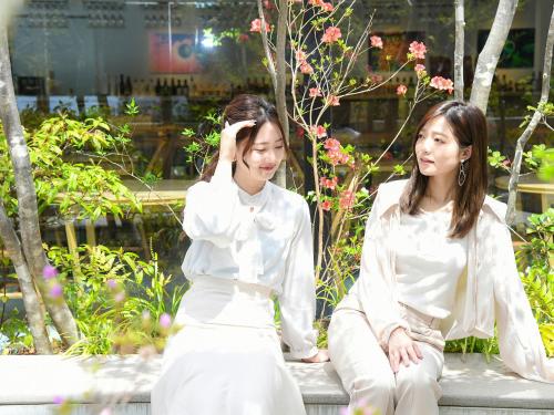 two women sitting on a bench in a garden at REF Kyoto Hachijoguchi by VESSEL HOTELS in Kyoto