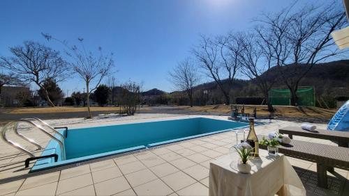 a swimming pool with a table and a bottle of wine at プール バーベキュー場付き 貸し切り別荘 in Sano