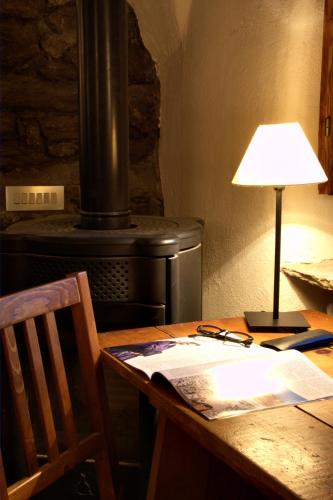a wooden table with a lamp and a stove at Baita del Plan in Pragelato