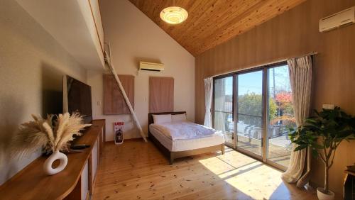 a bedroom with a bed and a large window at プール バーベキュー場付き 貸し切り別荘 in Sano