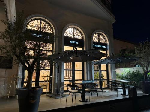a restaurant with tables and umbrellas in front of a building at Cosmopolita Boutique Hotel in Timişoara