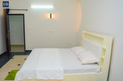 - un lit blanc dans un dortoir lumineux dans l'établissement Louis Vuitton, à Abomey-Calavi