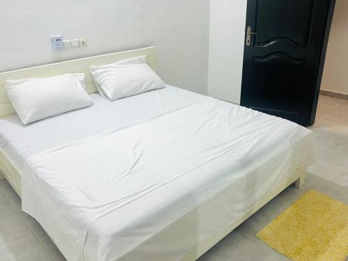- un grand lit blanc avec 2 oreillers dans l'établissement Louis Vuitton, à Abomey-Calavi
