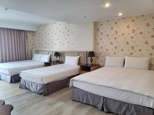 a hotel room with two beds with white sheets at Hotel Champs Elysées in Taichung