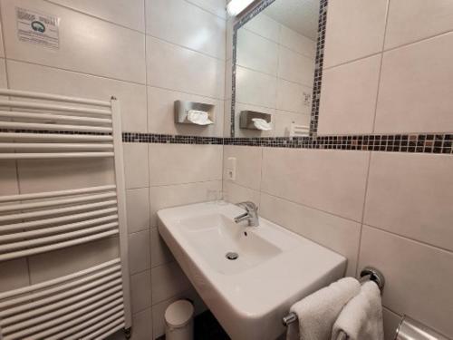 een witte badkamer met een wastafel en een spiegel bij Gasthaus Pension Donishäusle in Titisee-Neustadt