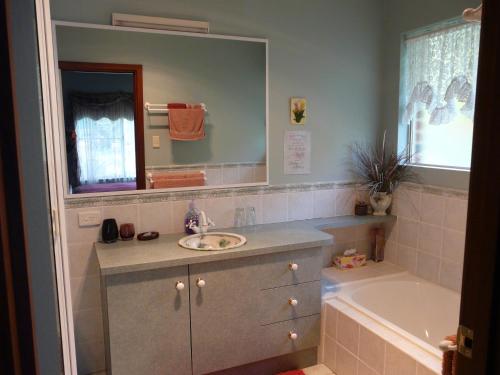 a bathroom with a sink and a tub and a mirror at Country Charm Retreat B&B in Donnybrook
