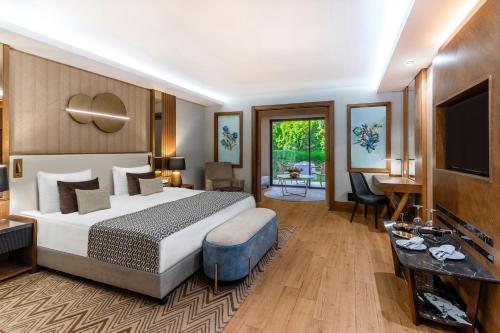 um quarto de hotel com uma cama e uma televisão em Susesi Luxury Resort em Belek