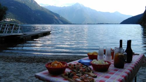 a table with drinks and baskets of food next to a lake at Agriturismo Val Codera in Verceia