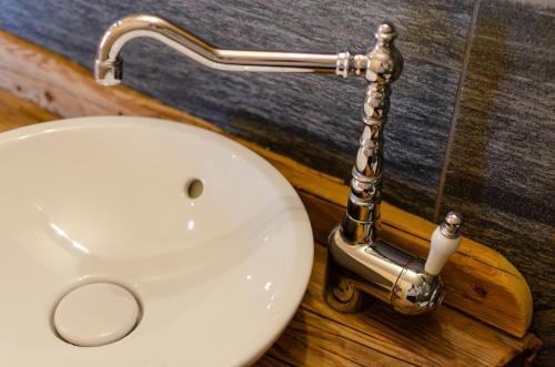 a white bathroom sink with a silver faucet at Hotel Arnika Wellness in Passo San Pellegrino