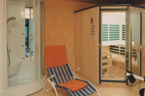 ein Badezimmer mit einem Stuhl, einer Badewanne und einer Dusche in der Unterkunft Appartements Platzis in Schruns-Tschagguns