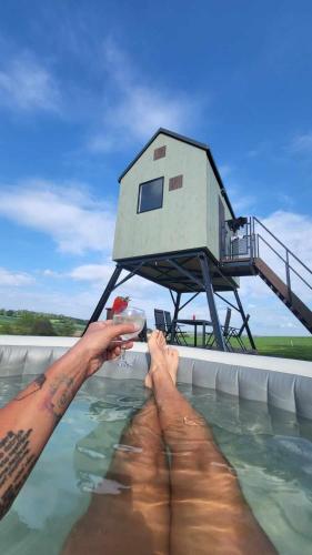 a man holding a wine glass in a swimming pool with a house at Posed Kubík in Žďár nad Sázavou